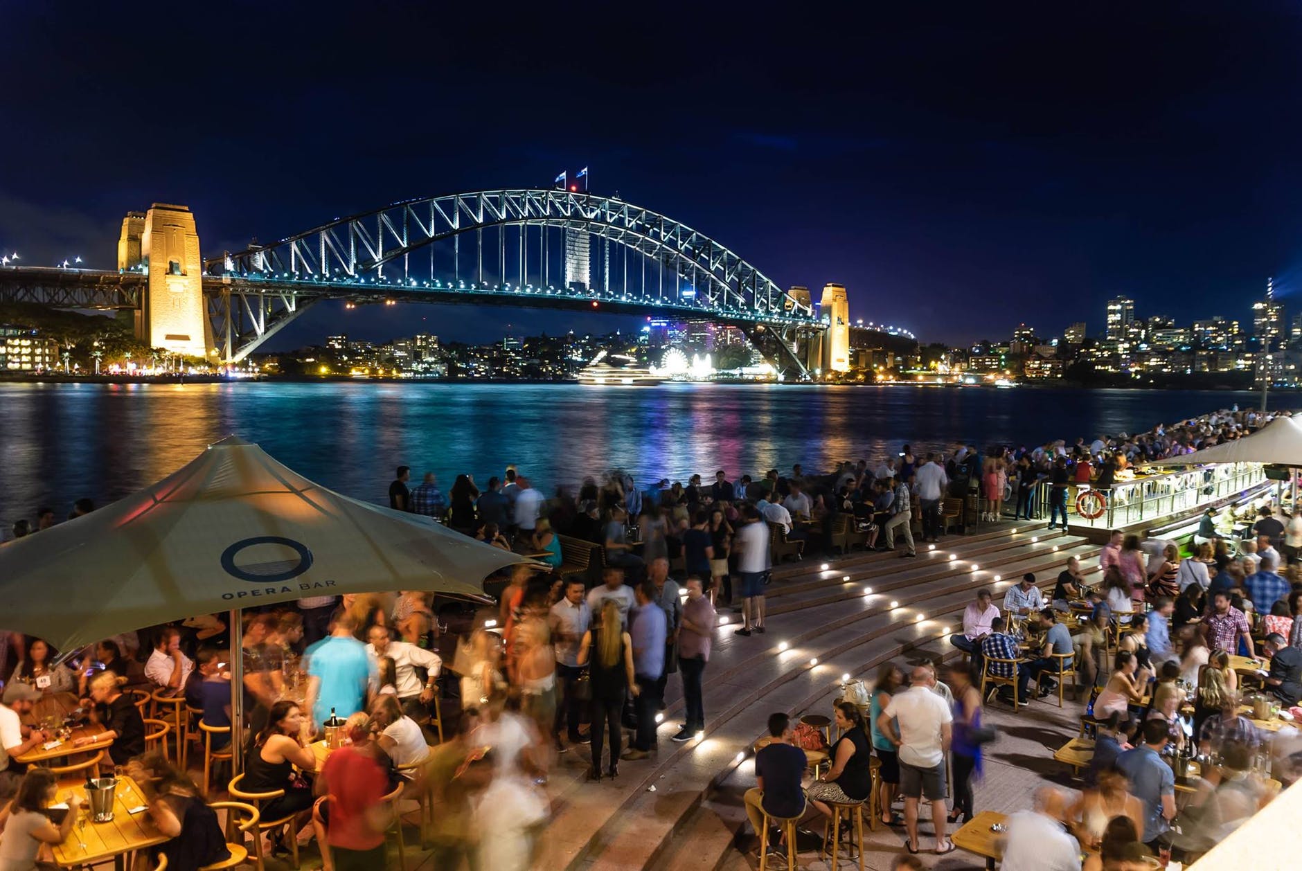 people sitting and standing near bridge during nighttime